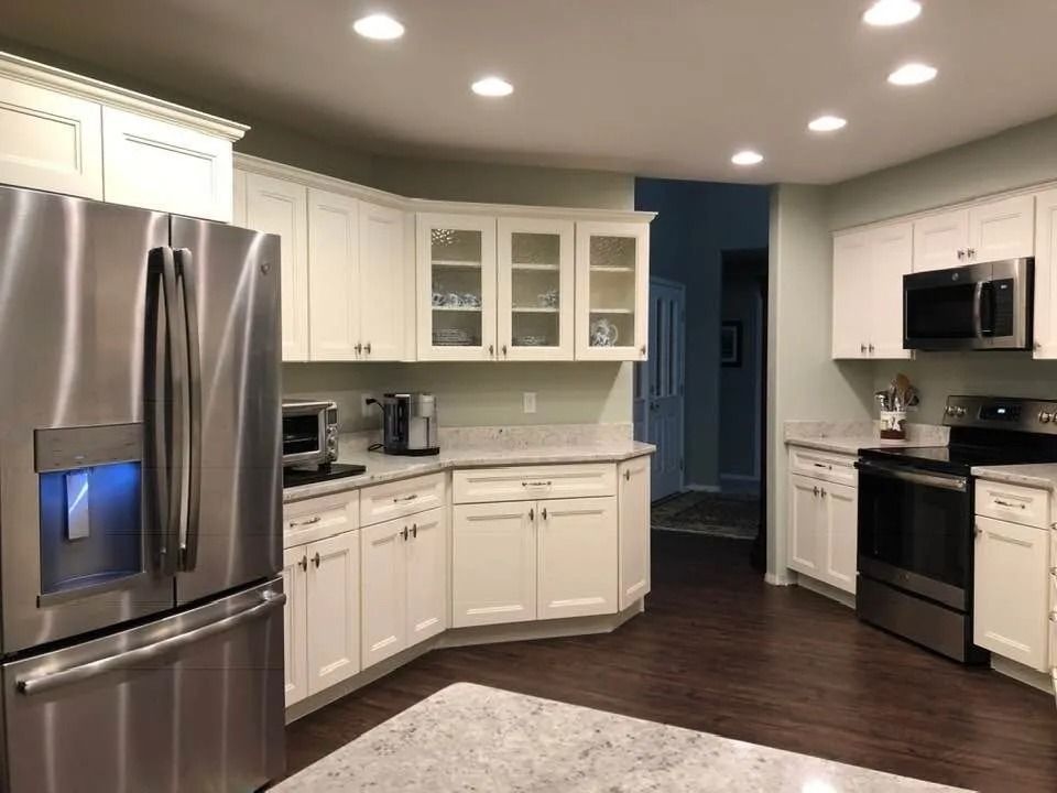 Modern kitchen with stainless steel appliances, white cabinets, and dark wood floor