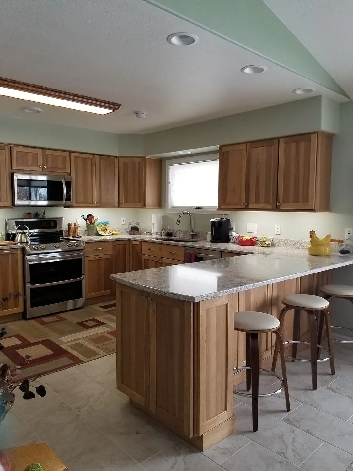 Kitchen with wood cabinets, stainless appliances, and a granite island with two stools.