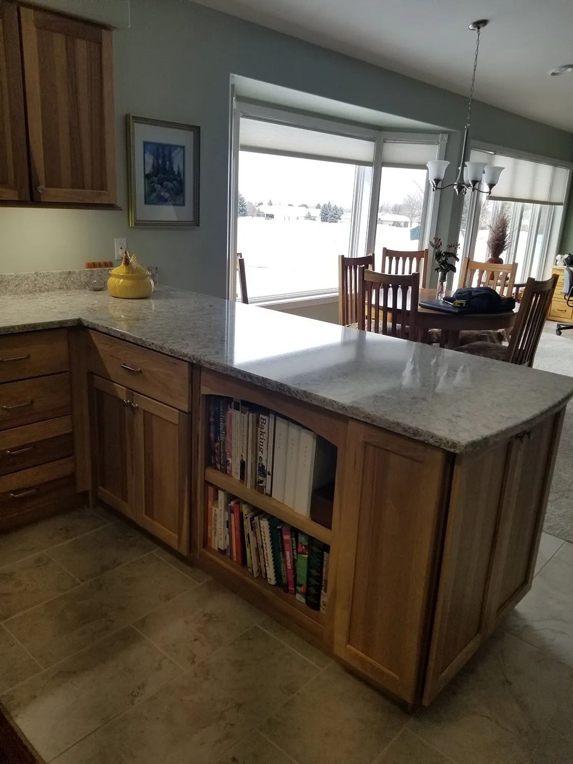Kitchen island with built-in bookshelf, granite countertop, and open view to dining area and patio doors