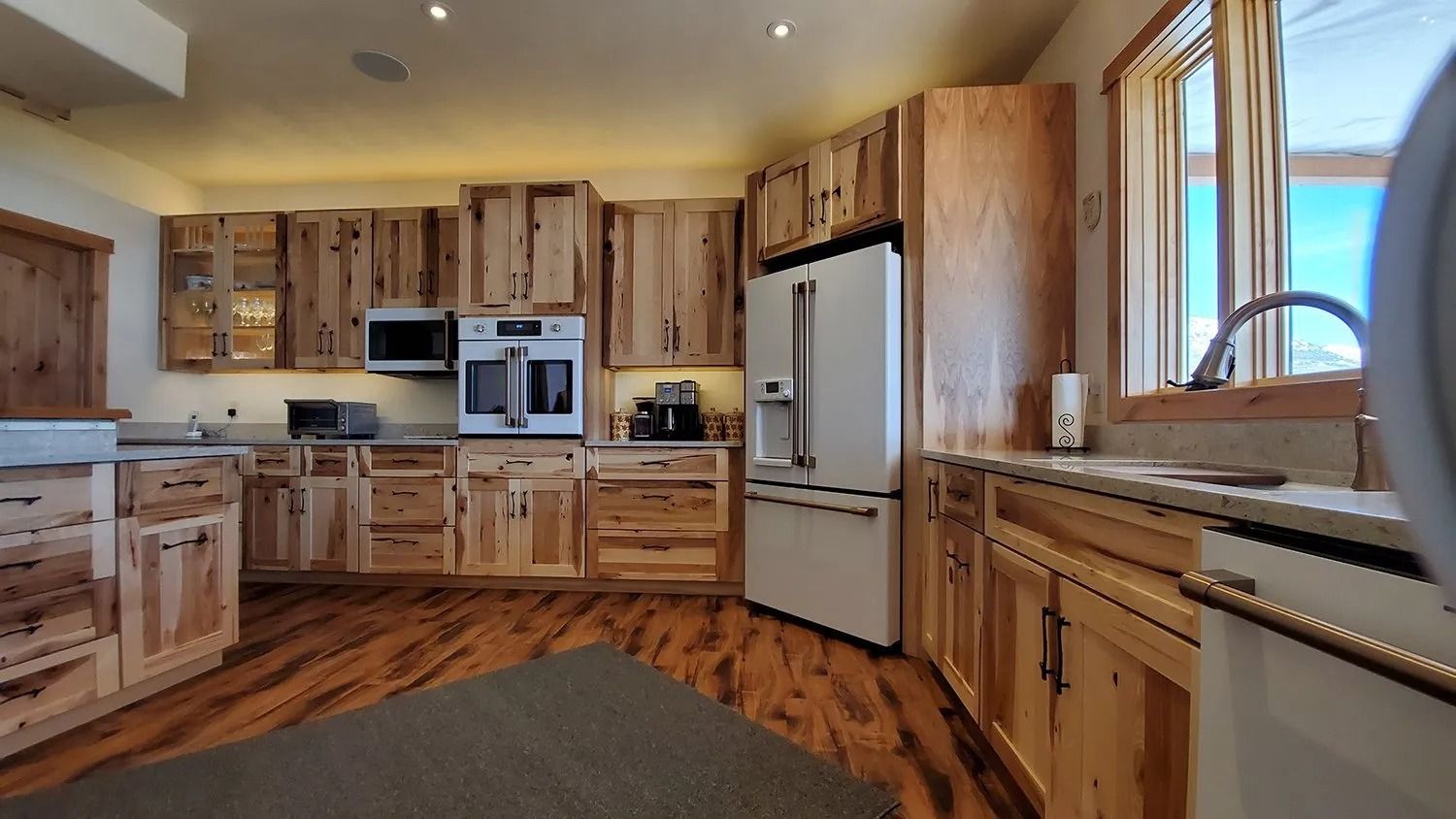 Spacious rustic kitchen with wood cabinets, stainless appliances, and a tiled floor.