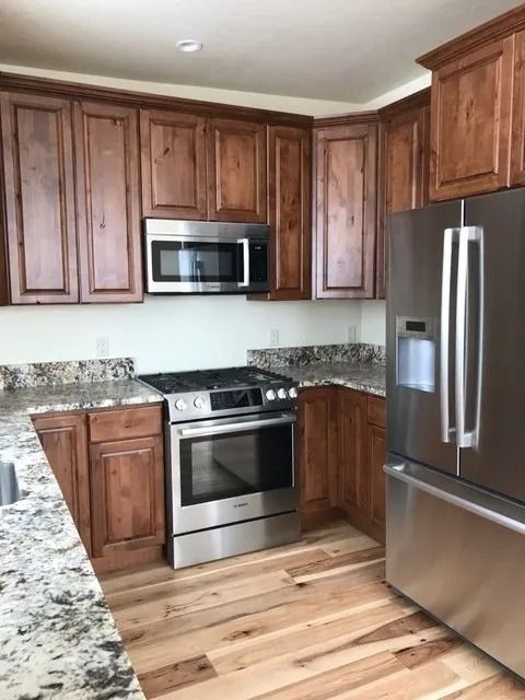 Modern kitchen with dark wood cabinets, stainless steel appliances, granite counters, and hardwood floors