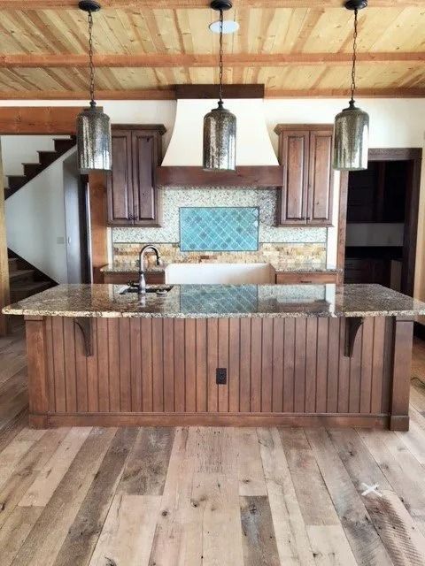 Modern kitchen with dark wood island, granite countertop, pendant lights, and tiled backsplash