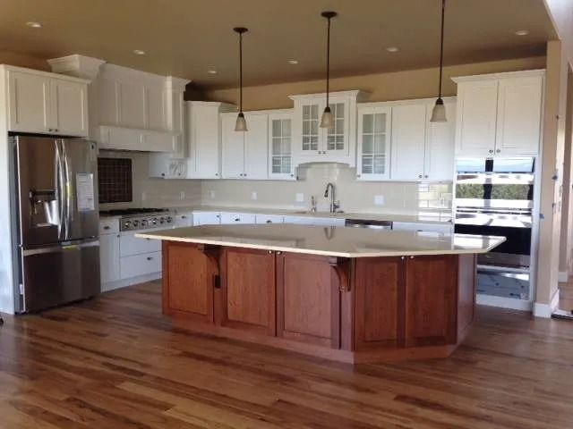 Modern kitchen with white cabinets, stainless steel appliances, and a large wood island on hardwood floors