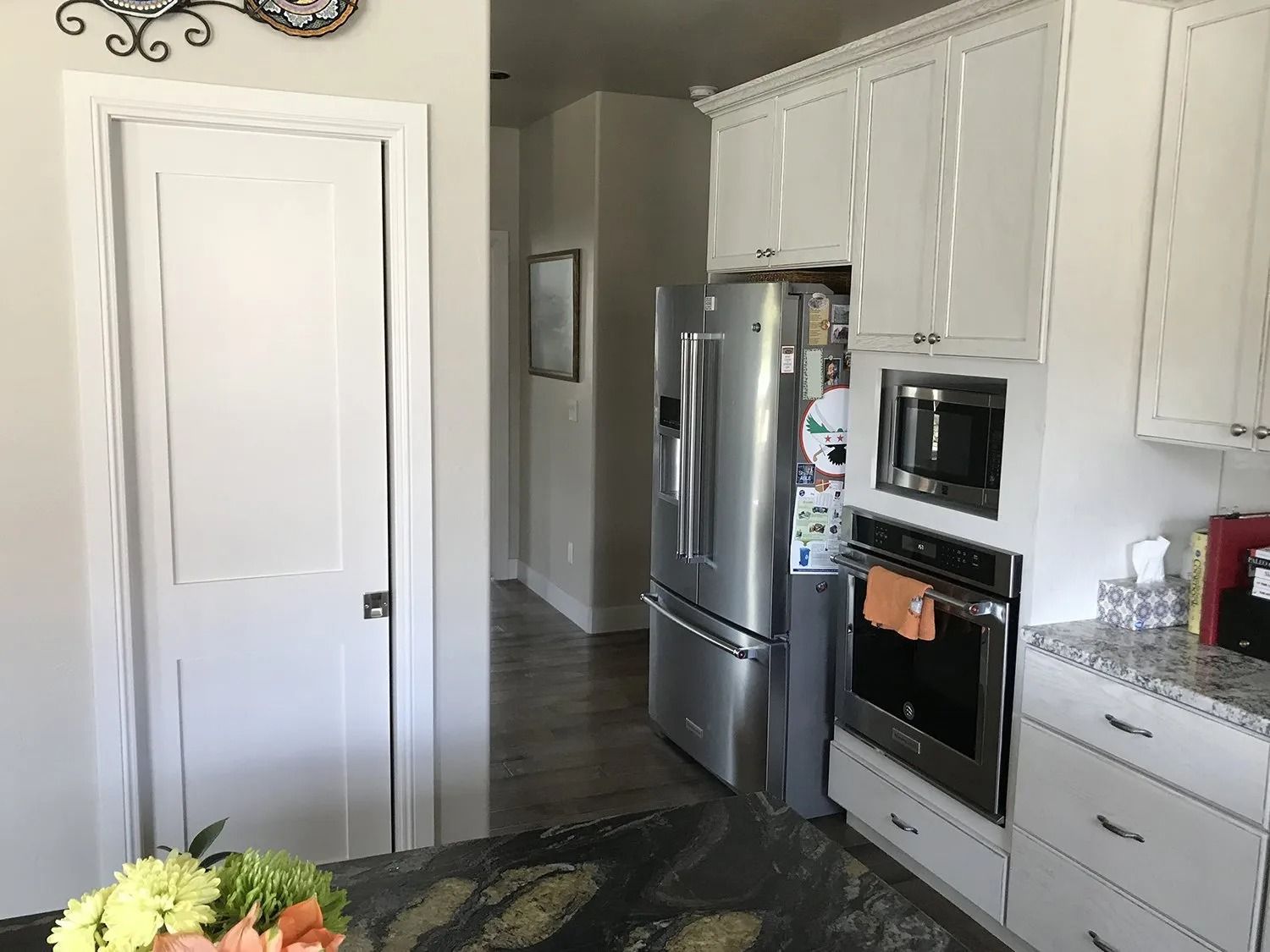 White kitchen with stainless steel appliances, tiled floor, and a large dark island in the foreground