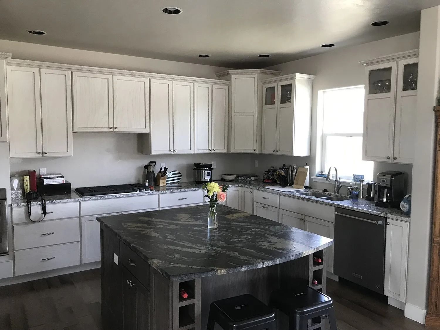 Modern kitchen with white cabinets, dark countertops, and a large black island under bright windows