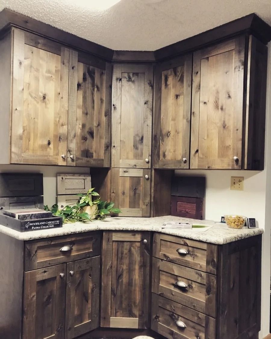 Corner kitchen with rustic wood cabinets, white countertop, and black stove.