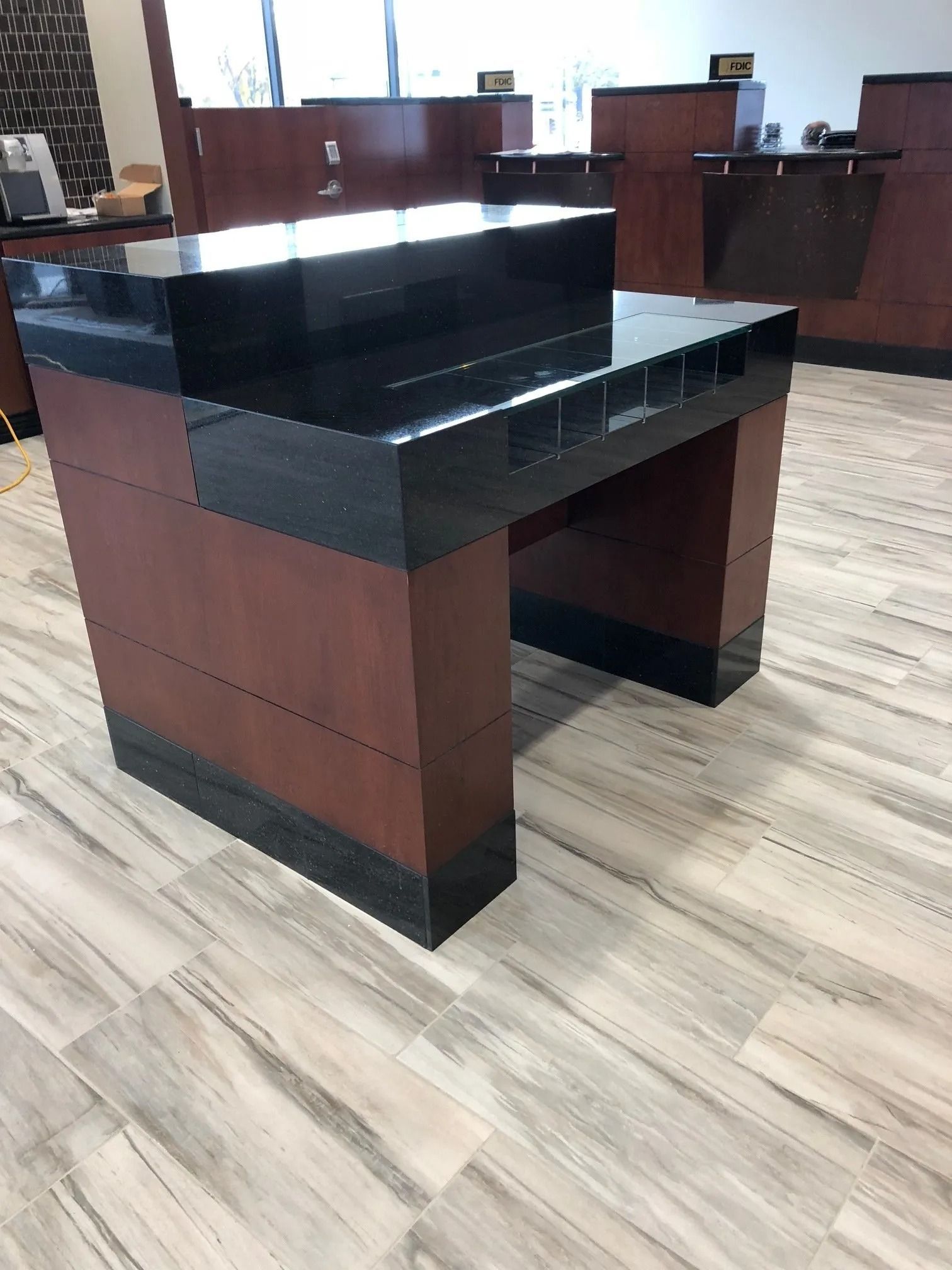 Wooden reception desk with black countertop in a lobby or office setting