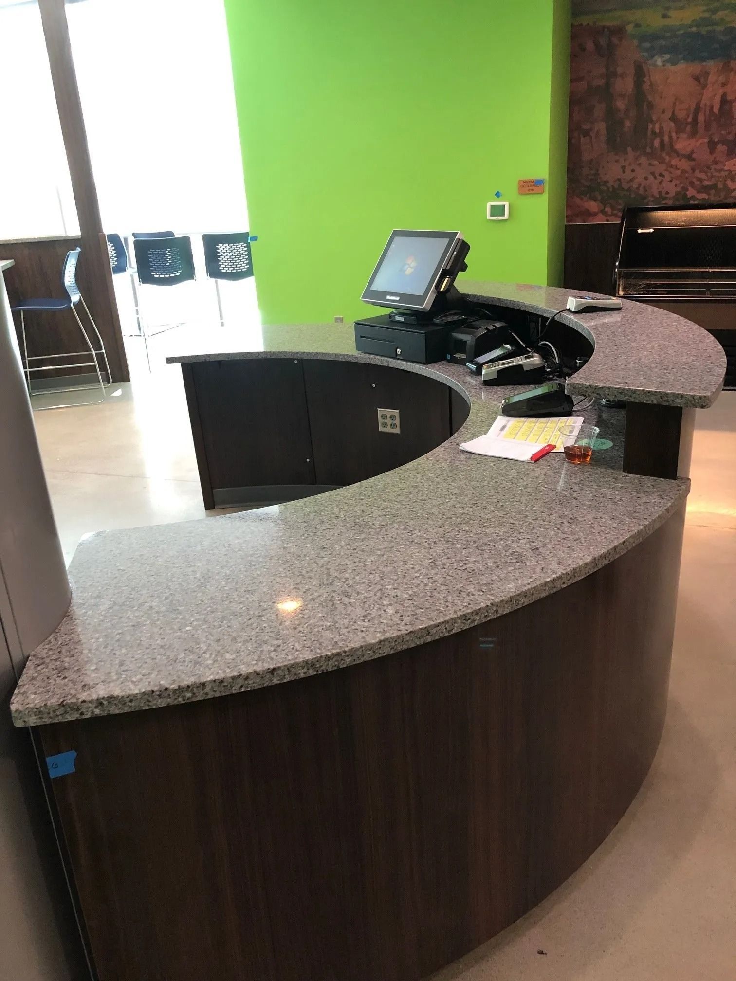 Curved hotel reception desk with gray countertop and black monitor in a bright lobby