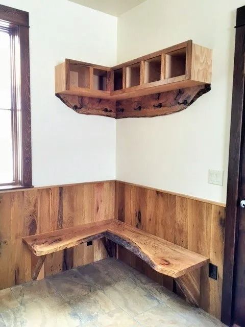 Small wooden corner desk and wall shelves in a simple room with wood paneling and a window