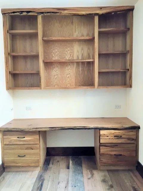 Wooden desk with drawers and matching wall-mounted shelving in a white room