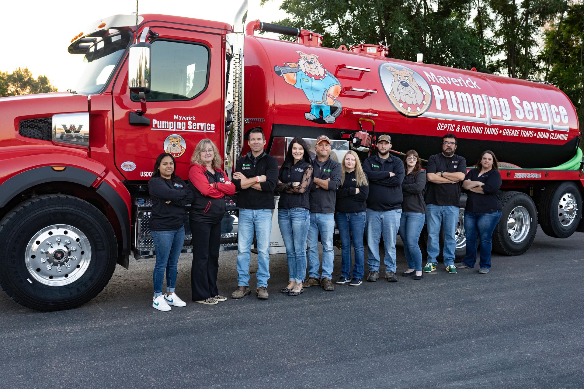 Group of people posing beside a red fuel truck with a large tank and logo.