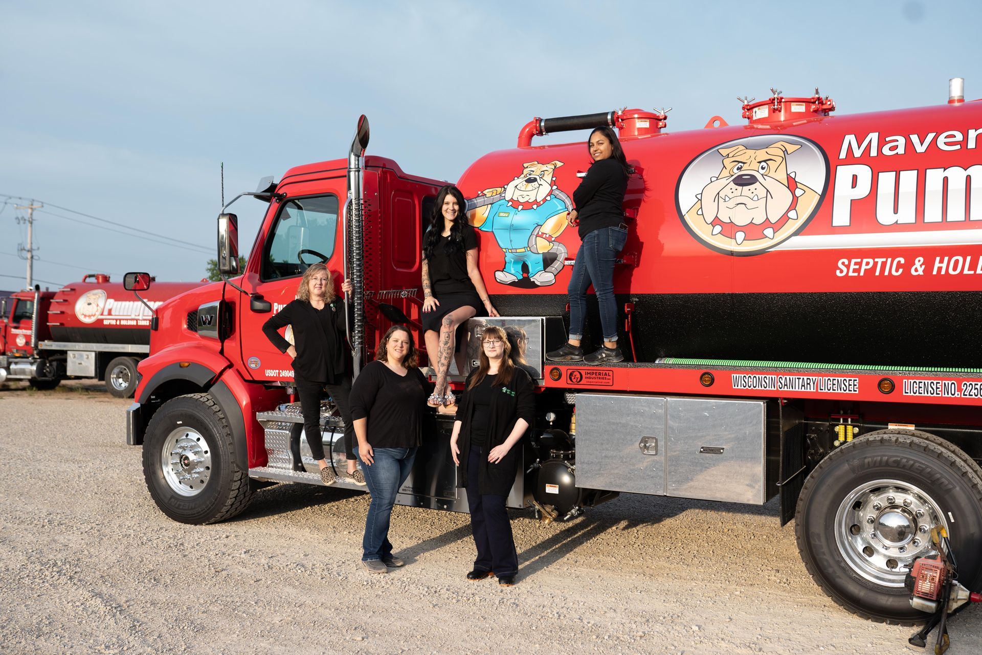 People posing in front of a red Maverik Pumpkin truck at a pumpkin patch event