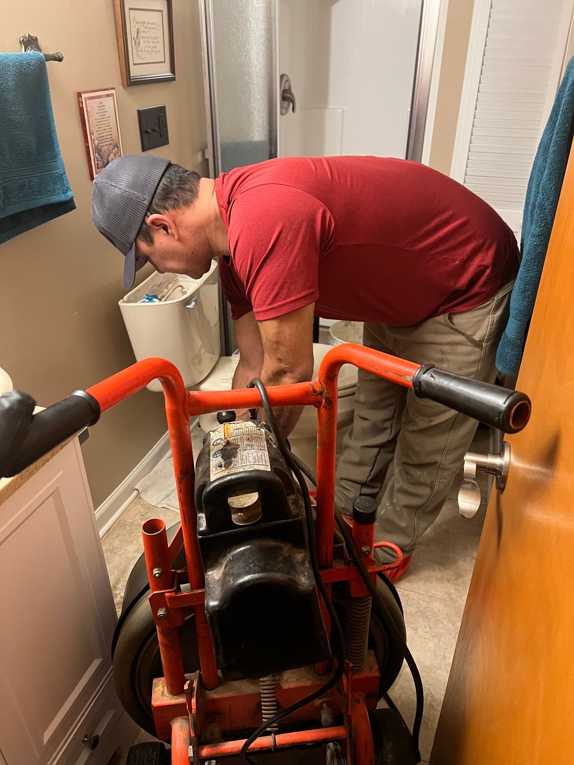 Man bending over an orange dolly in a narrow hallway, adjusting a heavy black object.