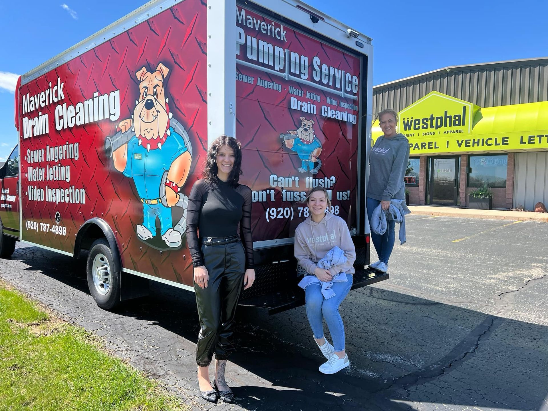 Two people posing beside a red carpet-cleaning truck in a parking lot.