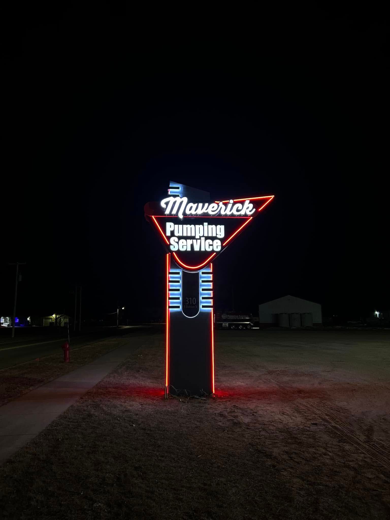 Neon “Maverick’s Gaming” sign glowing red and blue at night in a dark roadside field.