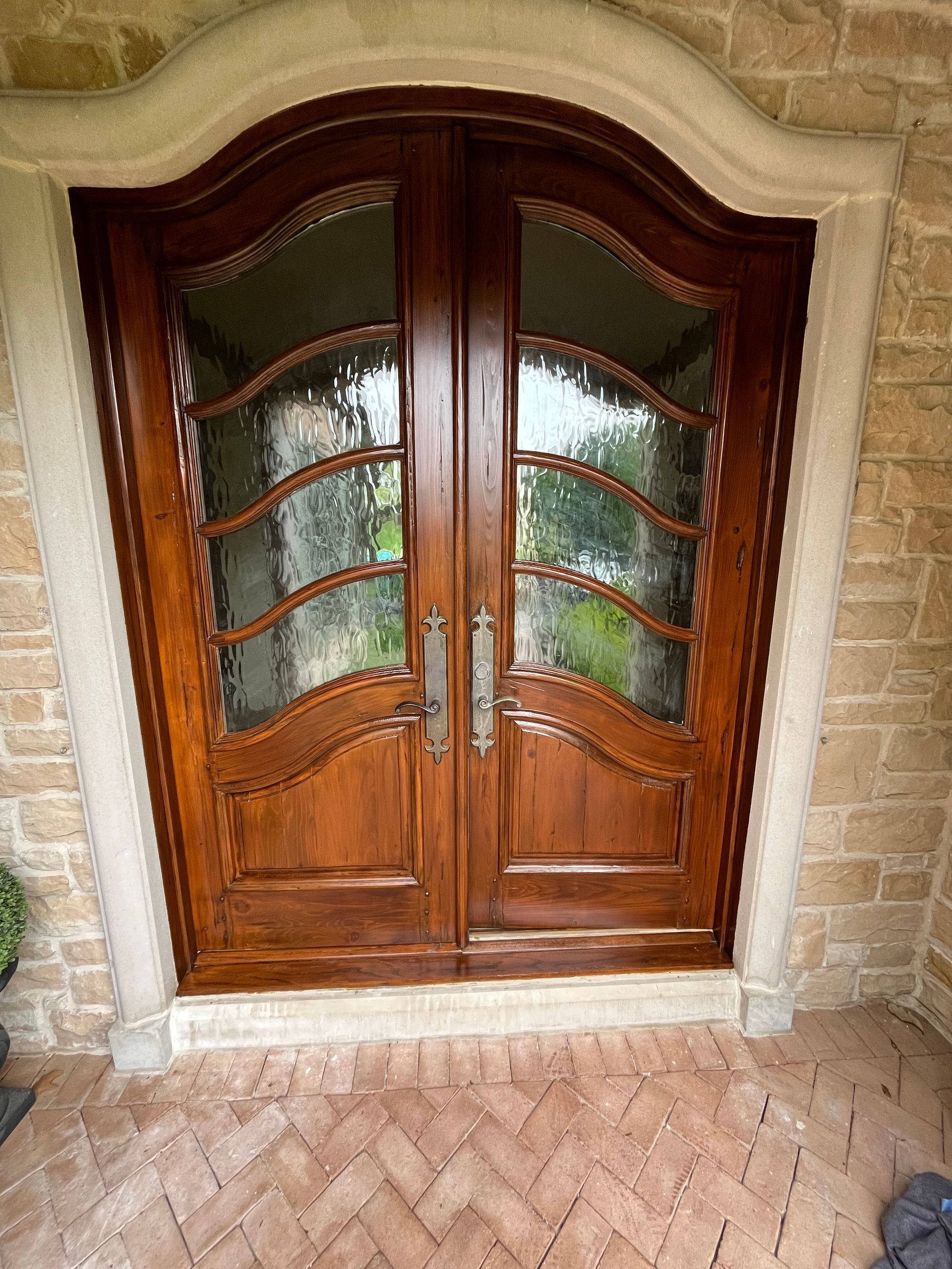 A large wooden door with a brick wall behind it.