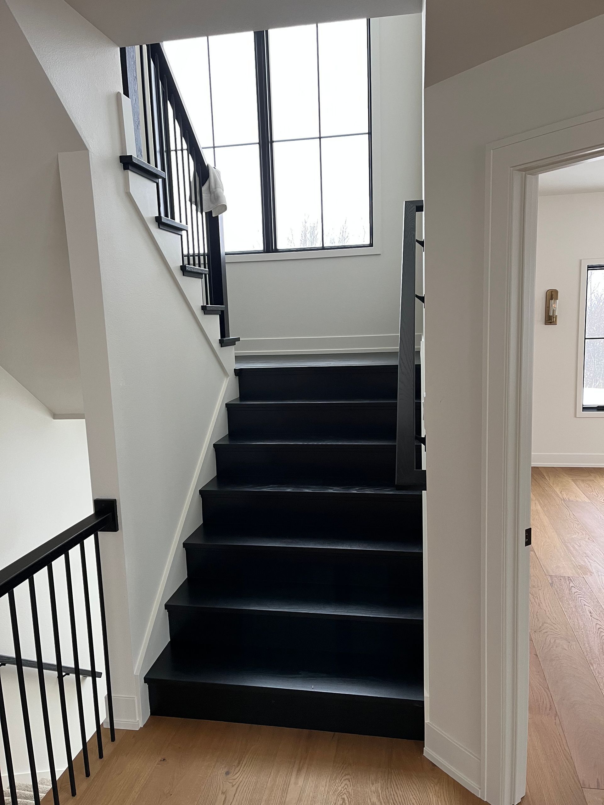 A staircase in a house with black steps and a white railing.
