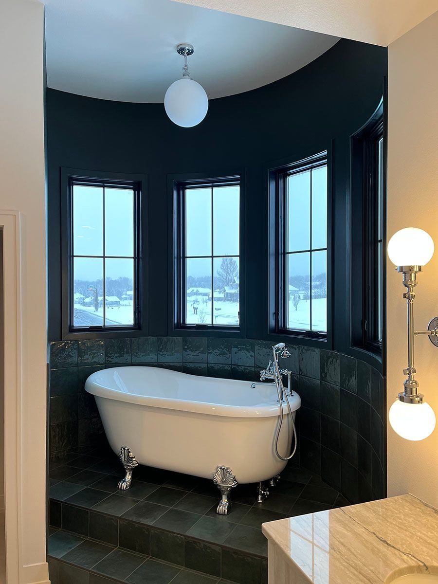 A bathroom with a bathtub and three windows.