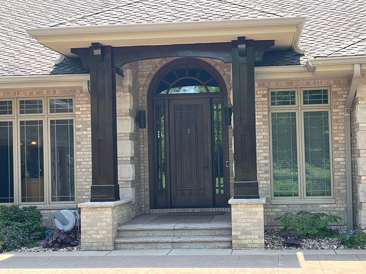 The front door of a brick house with a wooden door and arched porch.