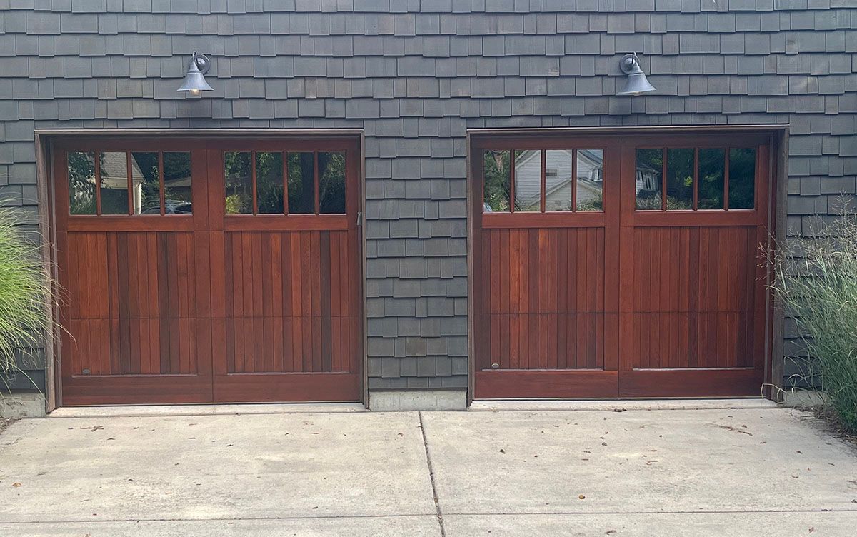 A pair of wooden garage doors on a brick building.