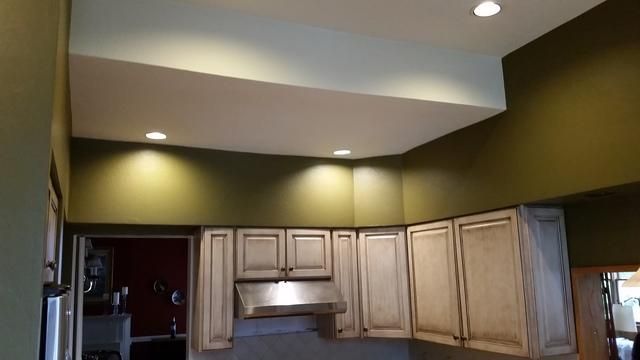 a kitchen with white cabinets and green walls
