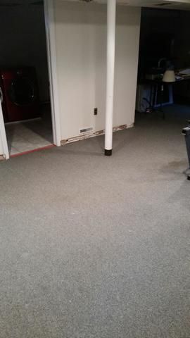 a basement with a carpeted floor and a white pole