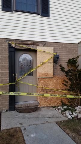 the front door of a house has been boarded up with yellow tape
