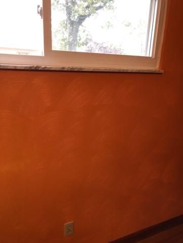 a room with orange walls and a window with a view of a tree