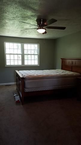 a bedroom with a bed, ceiling fan, and window