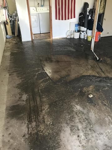 a dirty floor in a garage with a flag on the wall