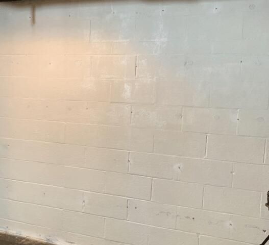 a white brick wall in a basement with a light shining on it