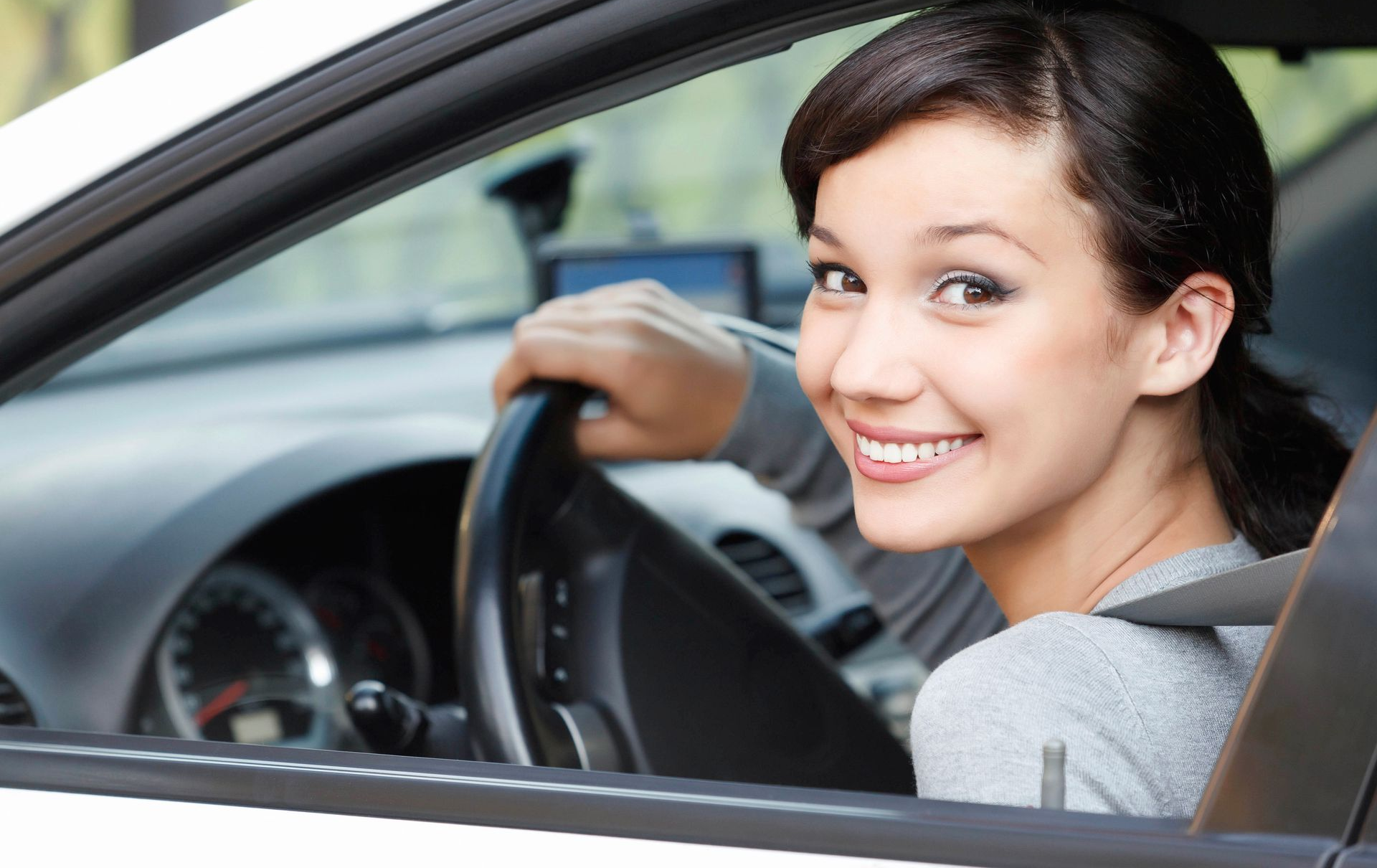 Woman smiling while driving a white car.