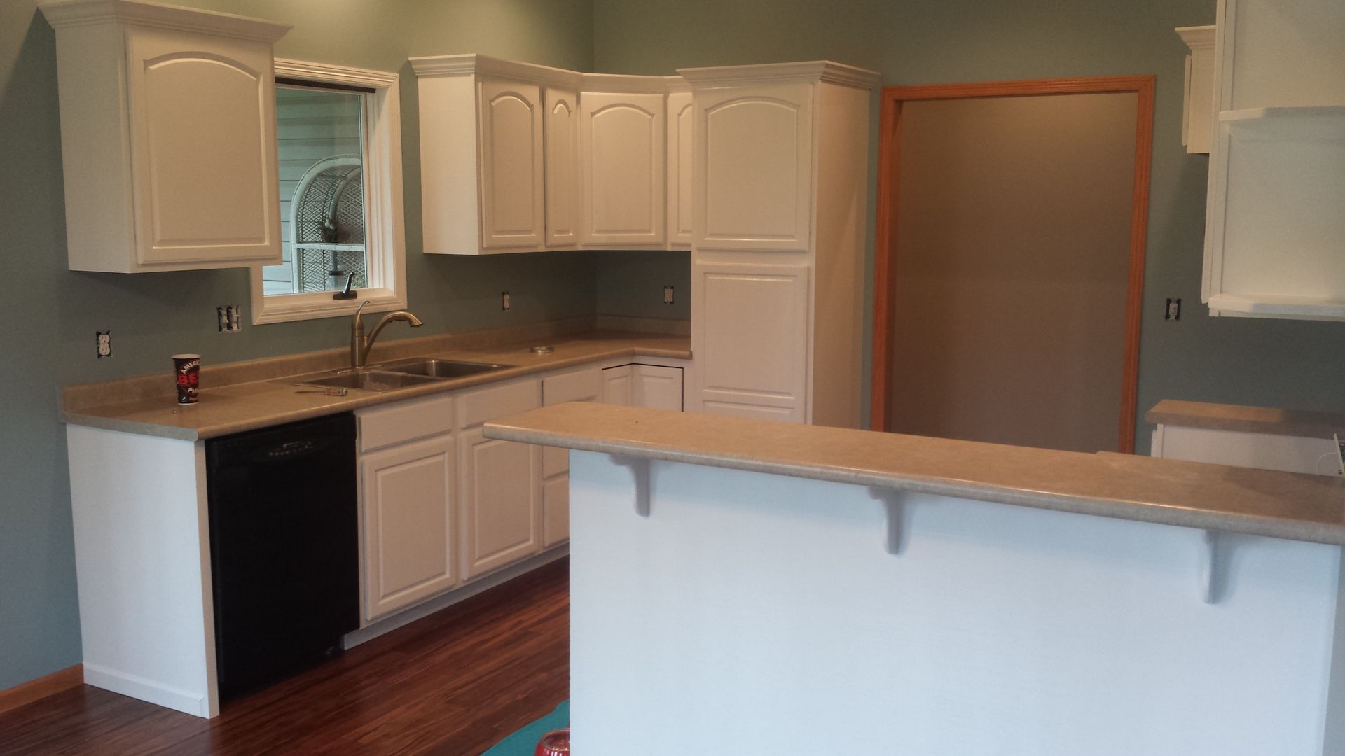An empty kitchen with white cabinets and a black dishwasher.