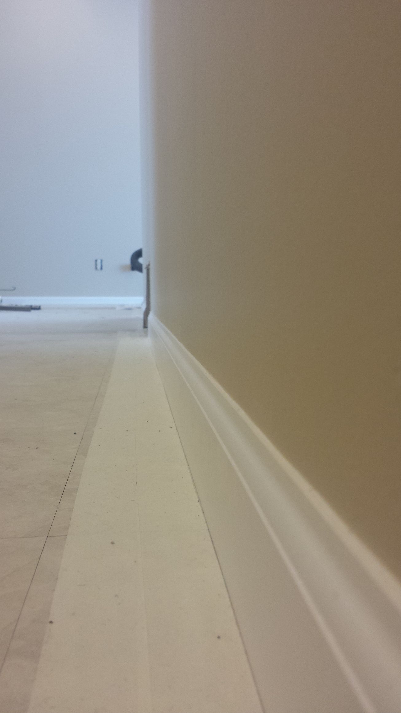 A corner of a room with a white molding and a white wall.