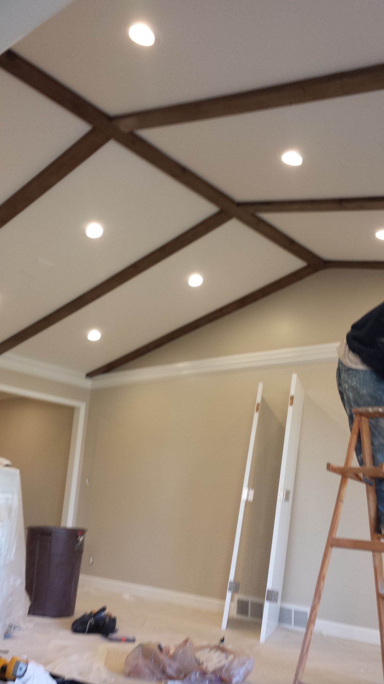 A man is standing on a ladder in a room with a vaulted ceiling.