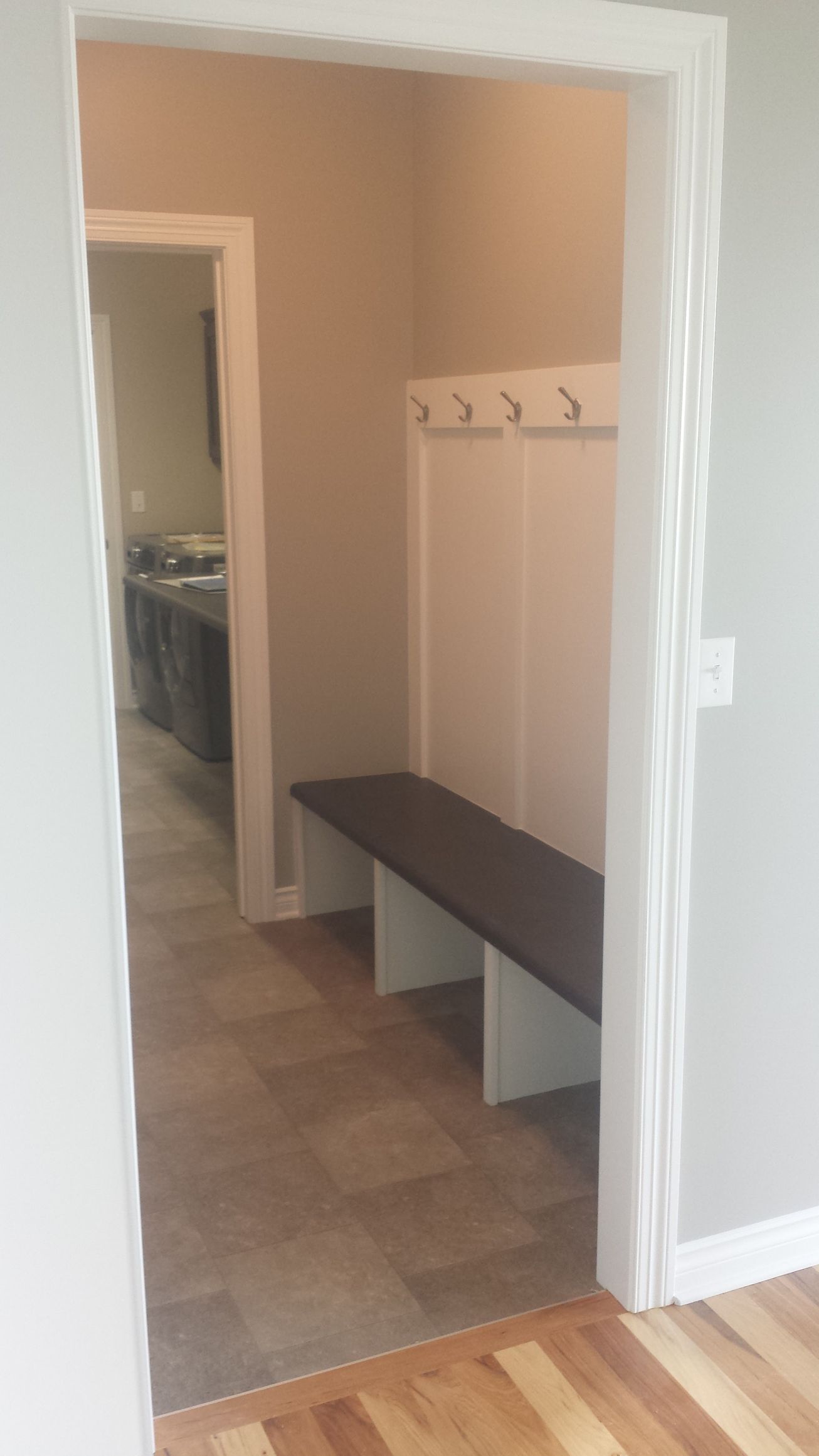 A hallway with a bench and hooks on the wall.