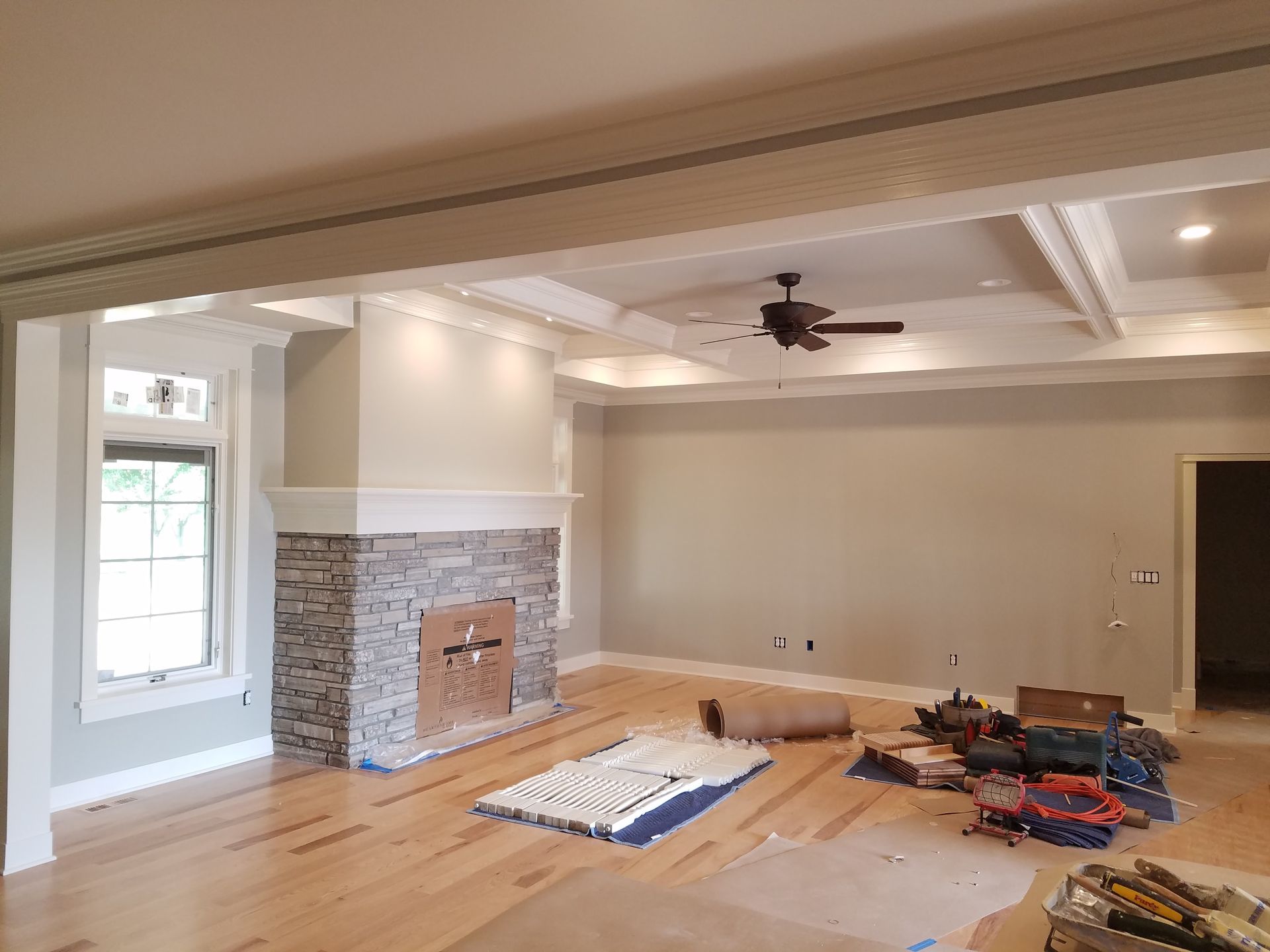 A living room with a fireplace and a ceiling fan.