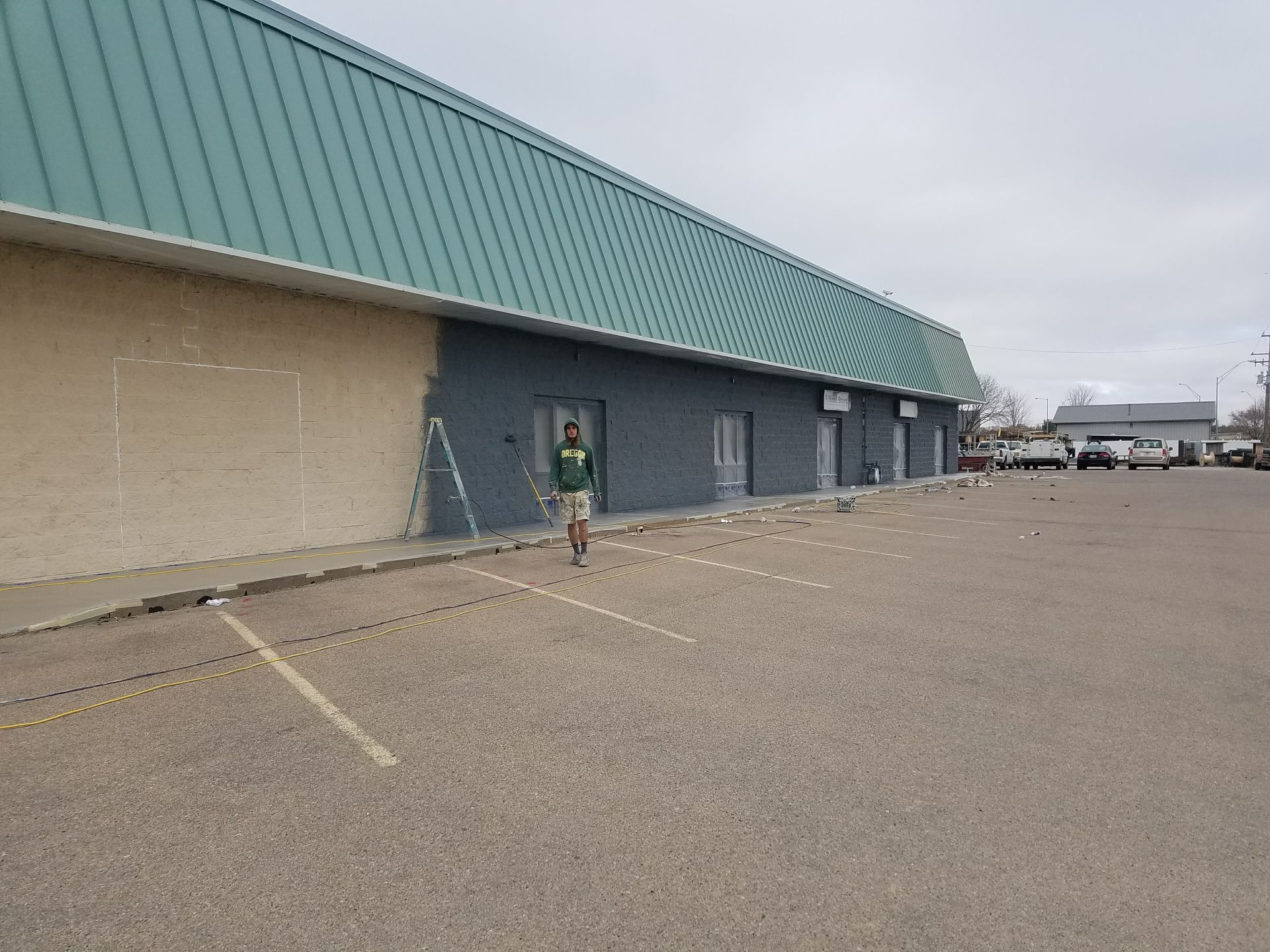A man is standing in front of a building that is being painted.