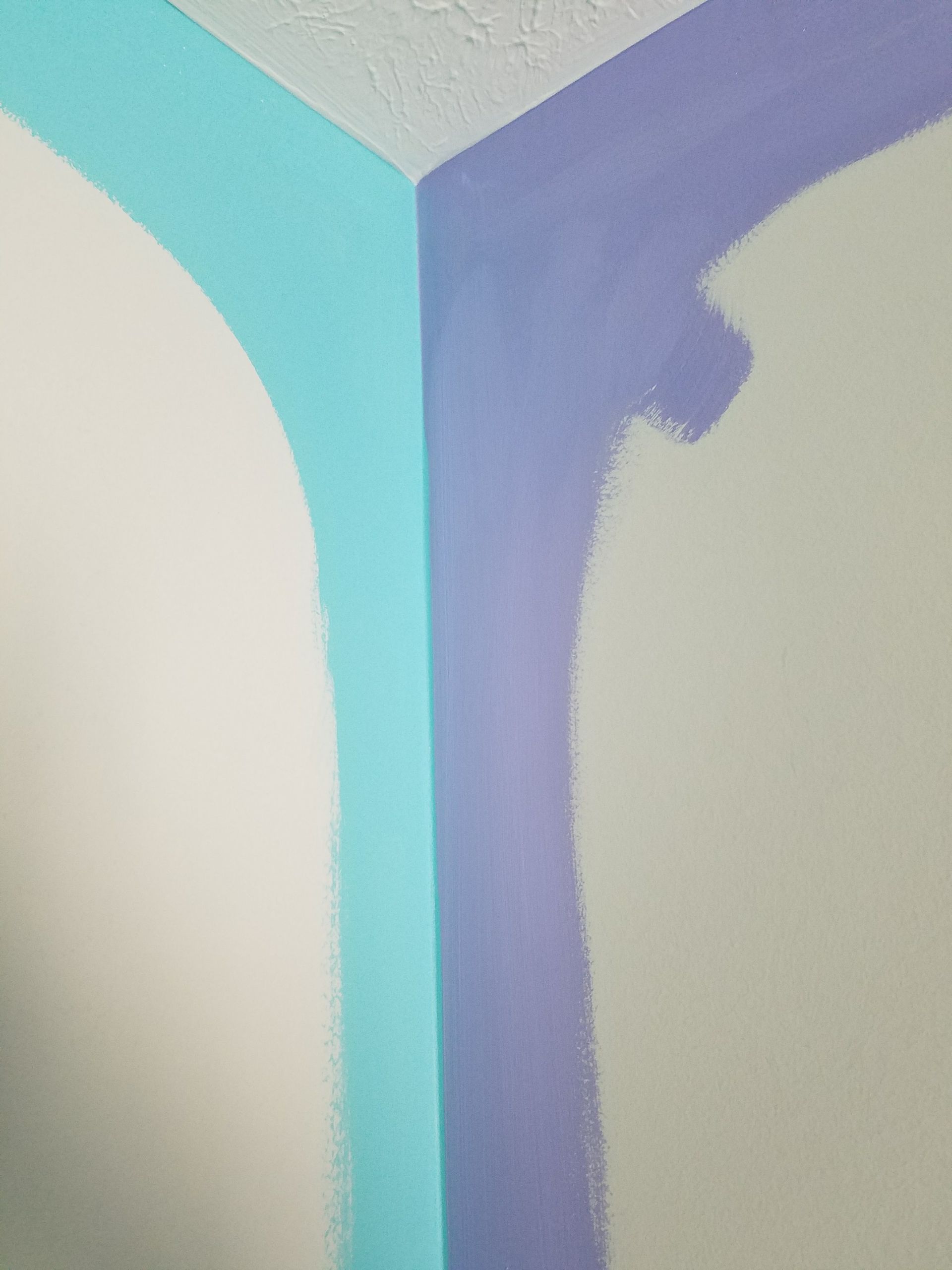 A corner of a room is being painted blue and purple.