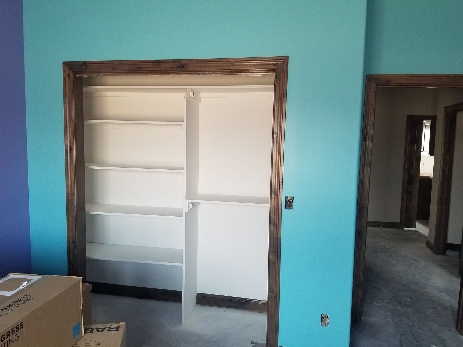 A closet in a room with blue walls and white shelves