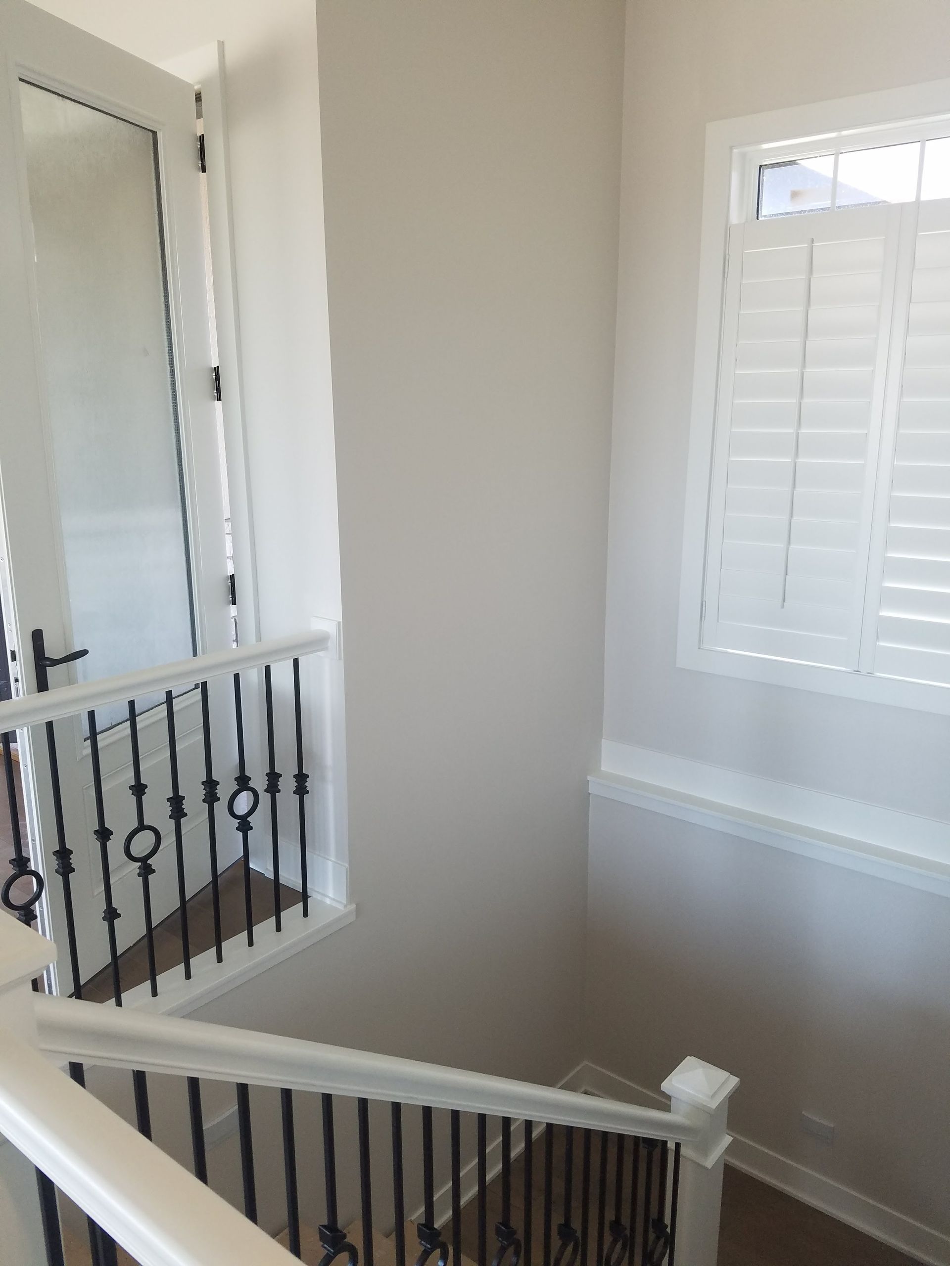 A staircase with a wrought iron railing and shutters on the windows