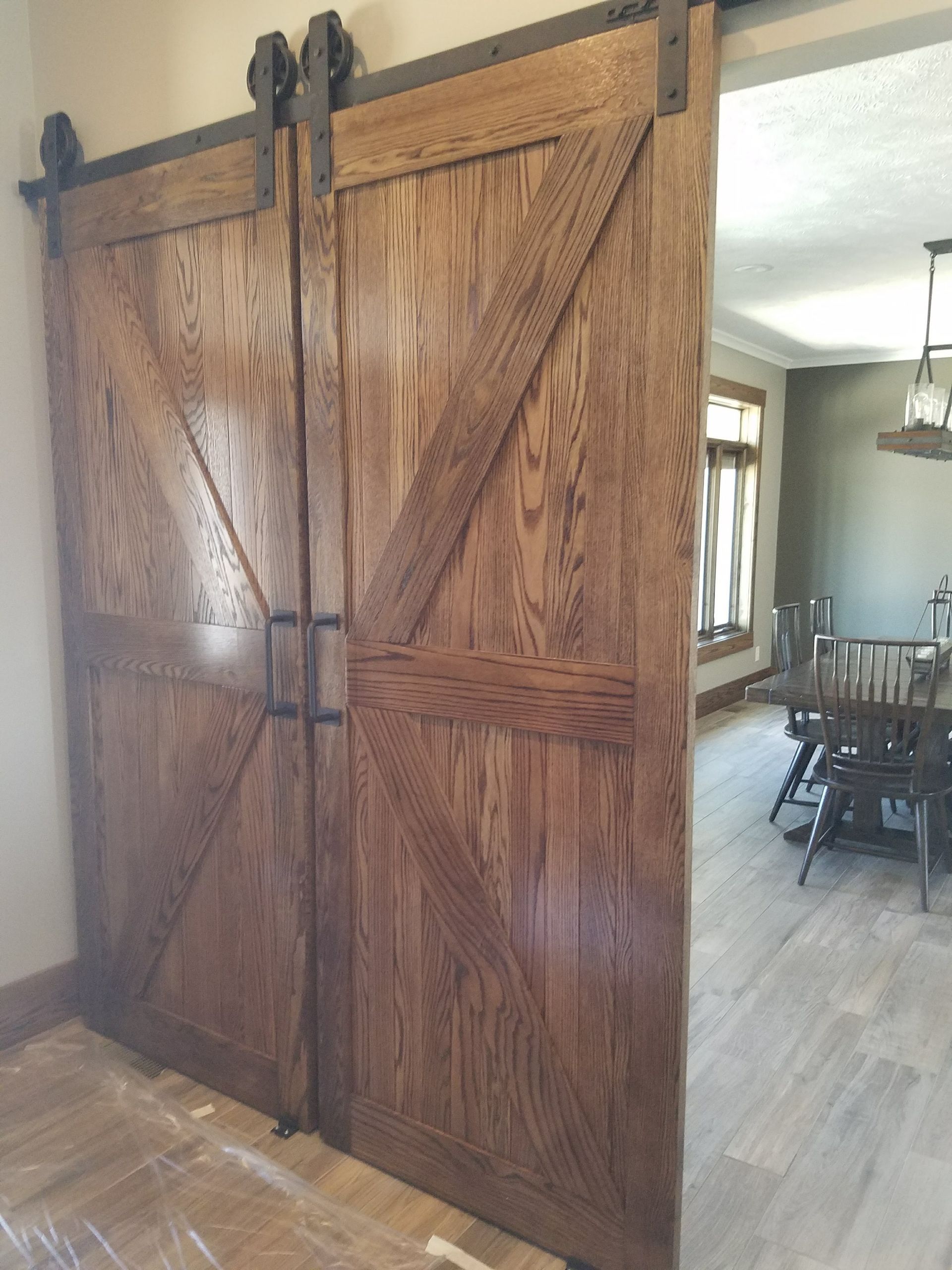 A pair of wooden sliding barn doors leading to a dining room.
