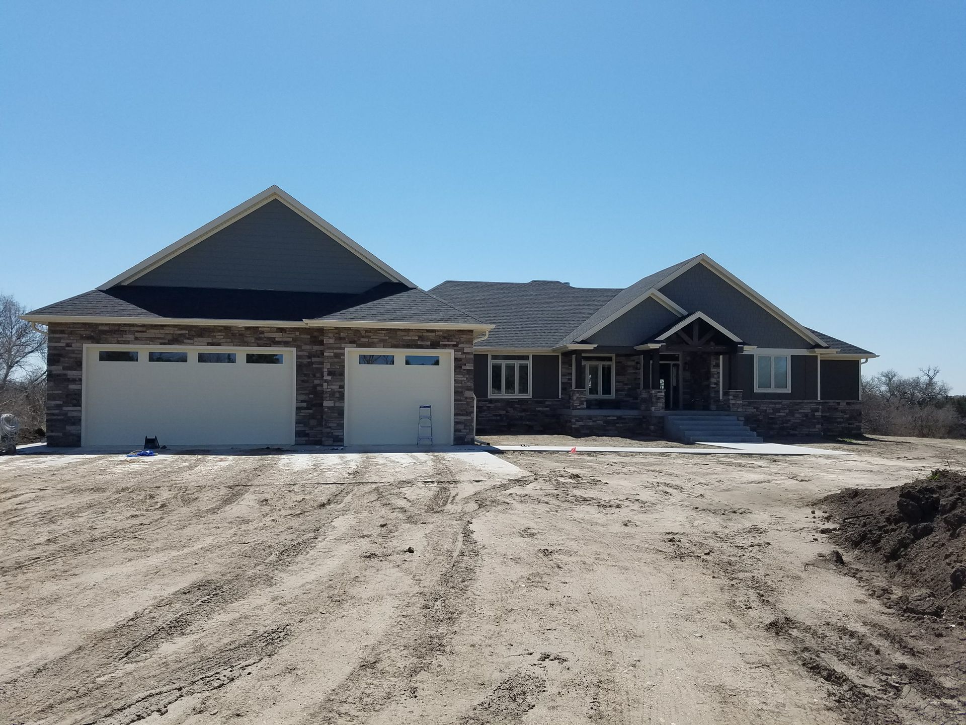 A large house is sitting in the middle of a dirt field.