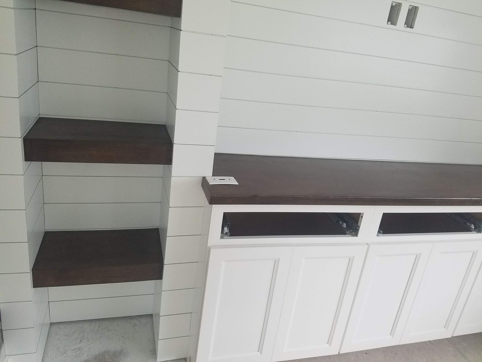 A kitchen with white cabinets and wooden shelves.