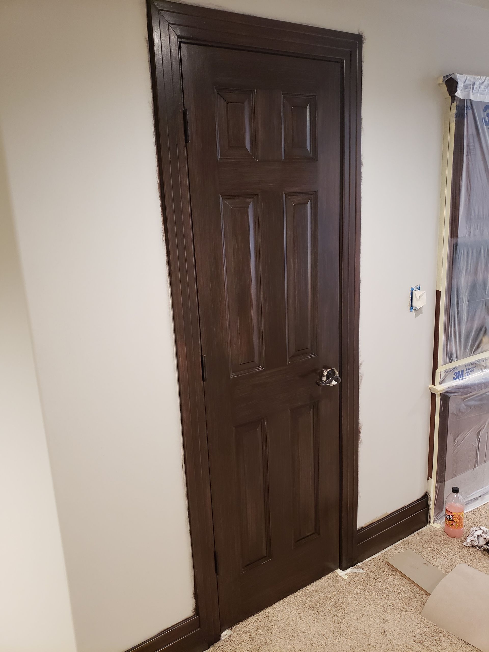 A brown door is sitting in a room next to a white wall.