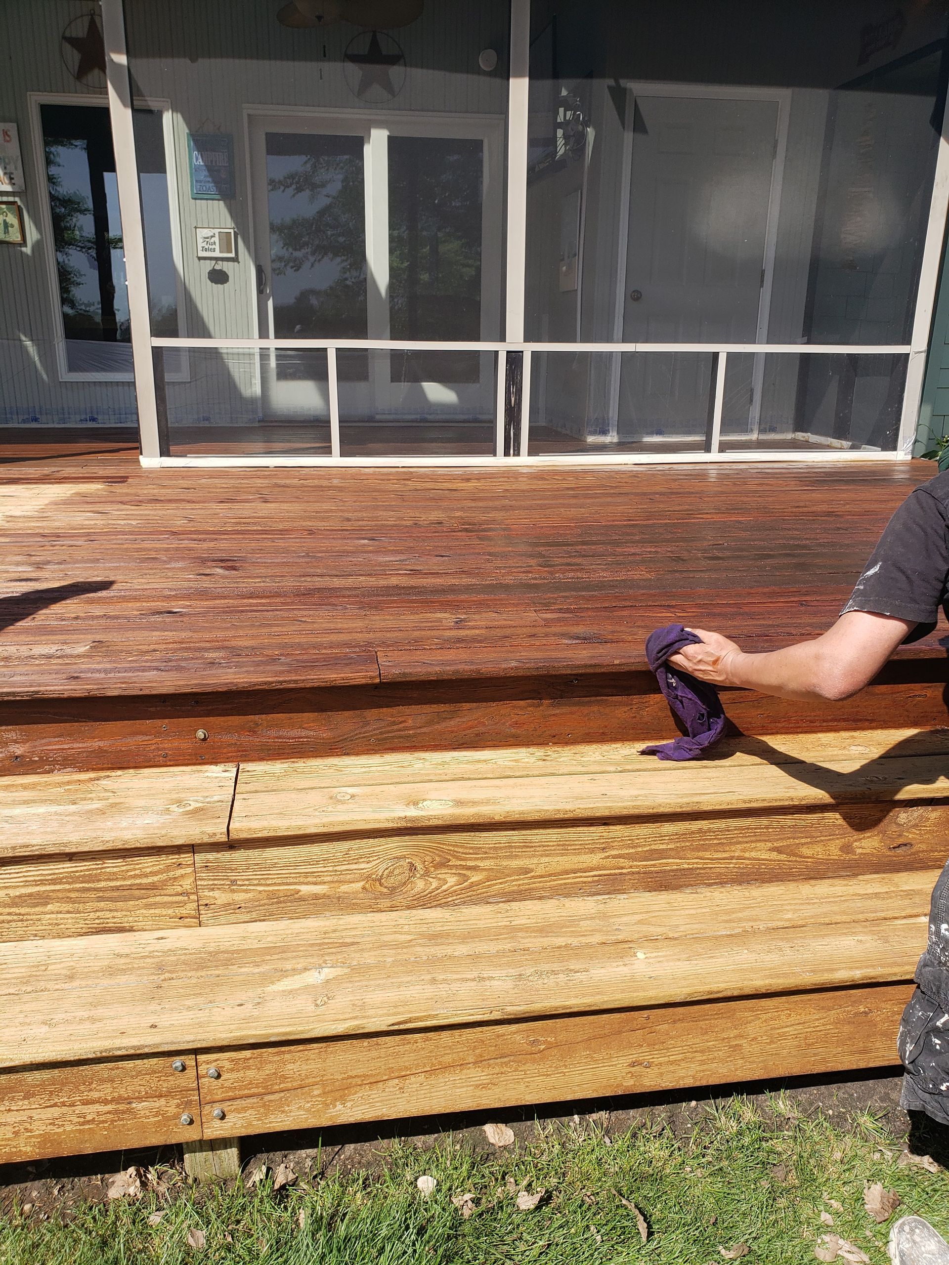 A man is sanding a wooden deck with a sander.
