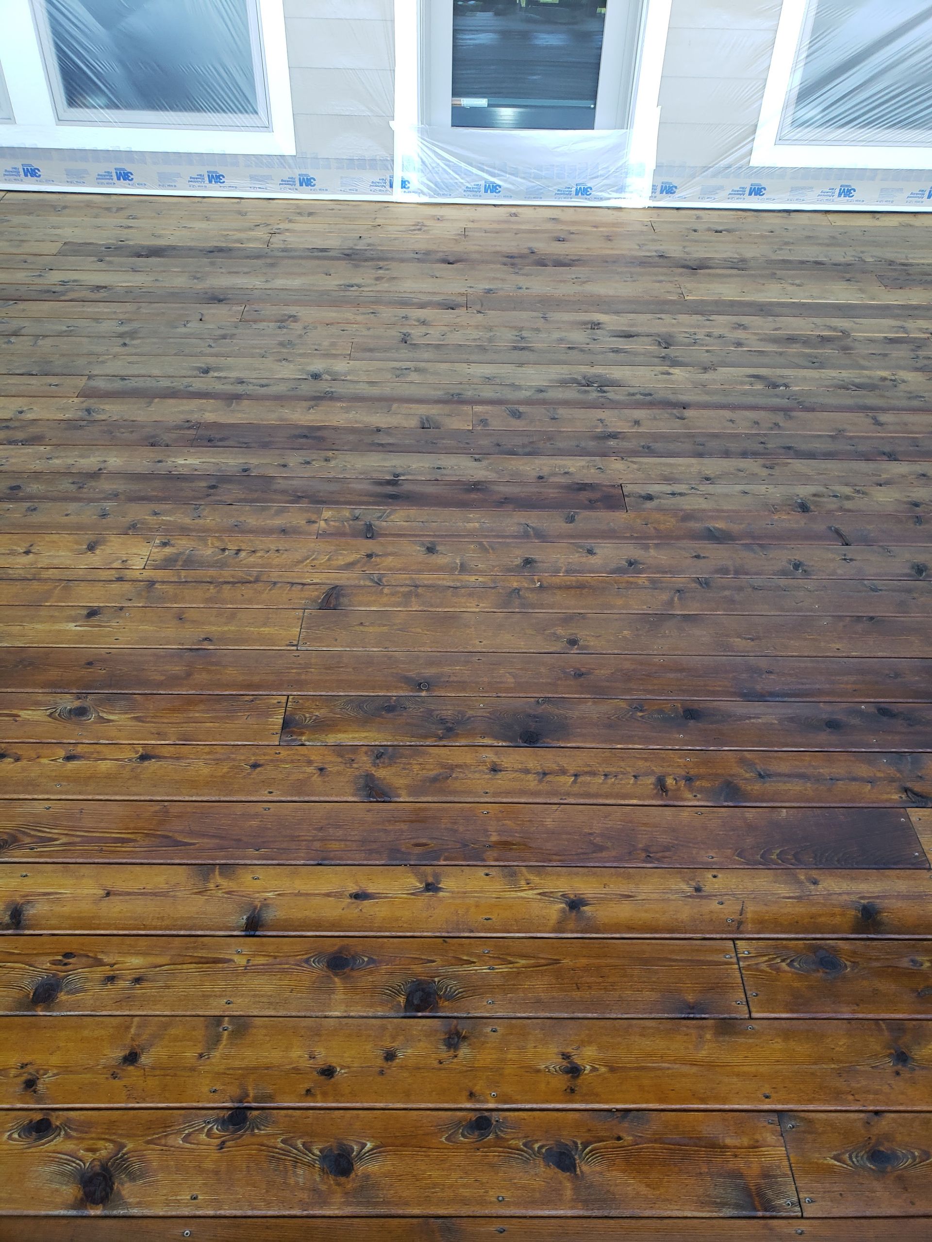 A close up of a wooden deck with a window in the background.