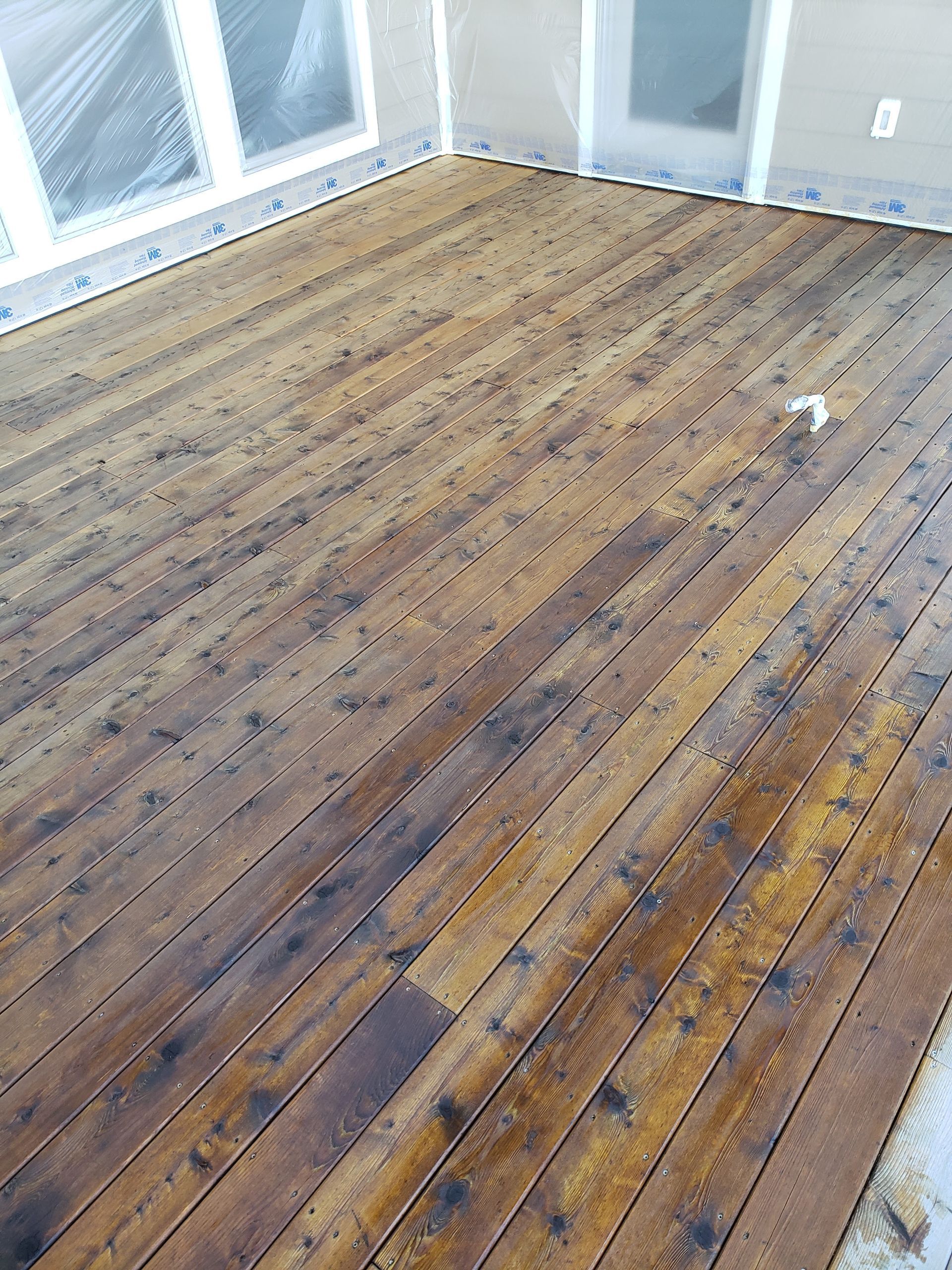 A wooden deck in a room with a lot of windows.