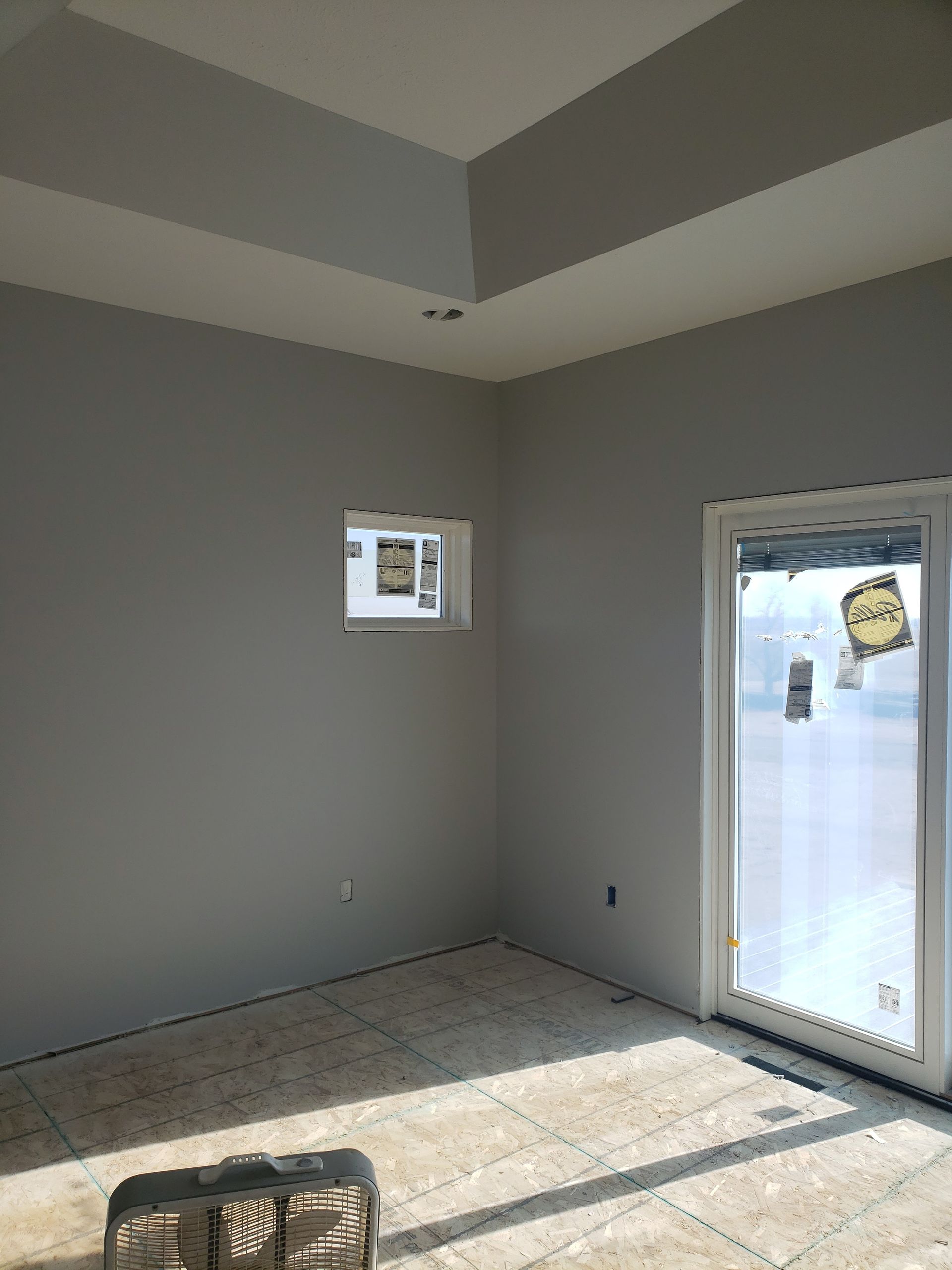 An empty room with a sliding glass door and two windows.