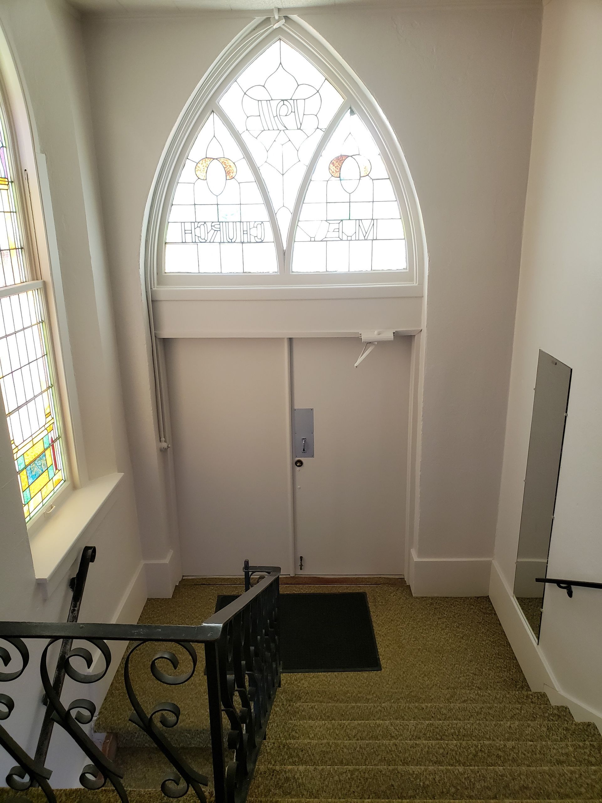 Stairs leading up to a door with a stained glass window
